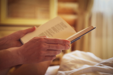 Woman reading book in bedroom, closeup view
