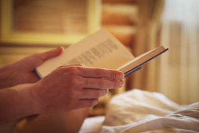 Photo of Woman reading book in bedroom, closeup view