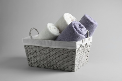 Photo of Basket of fresh towels on grey background