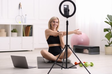 Smiling sports blogger streaming online fitness lesson at home