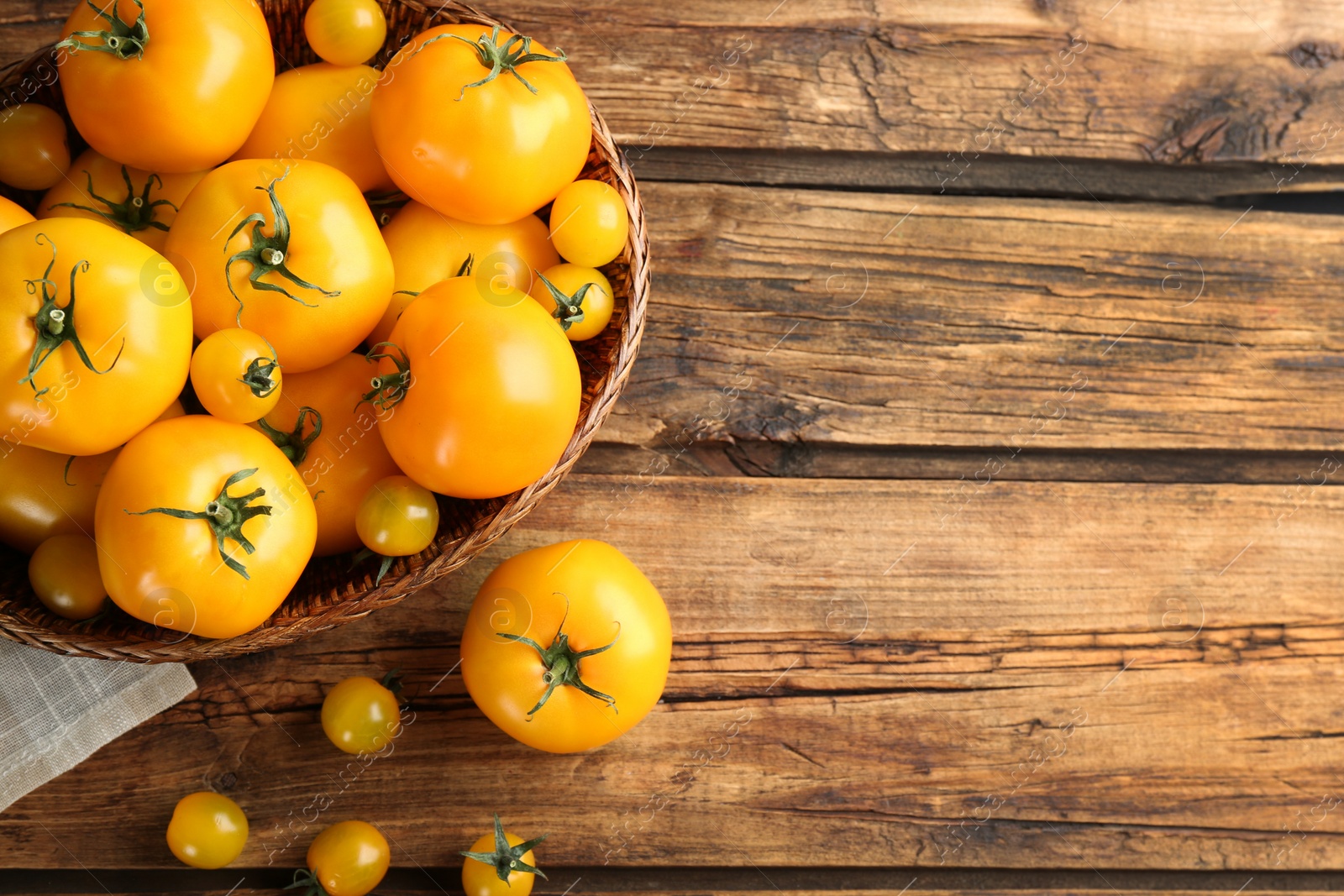 Photo of Ripe yellow tomatoes on wooden table, flat lay. Space for text