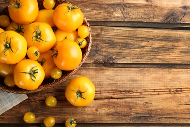 Photo of Ripe yellow tomatoes on wooden table, flat lay. Space for text