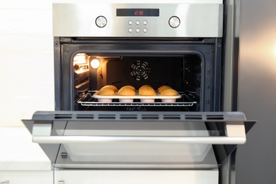 Baking pan with cupcakes in modern oven