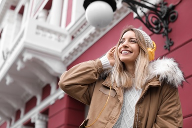 Young woman with headphones listening to music outdoors. Space for text