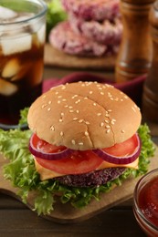 Photo of Tasty vegetarian burger with beet patty and sauce on wooden table, closeup