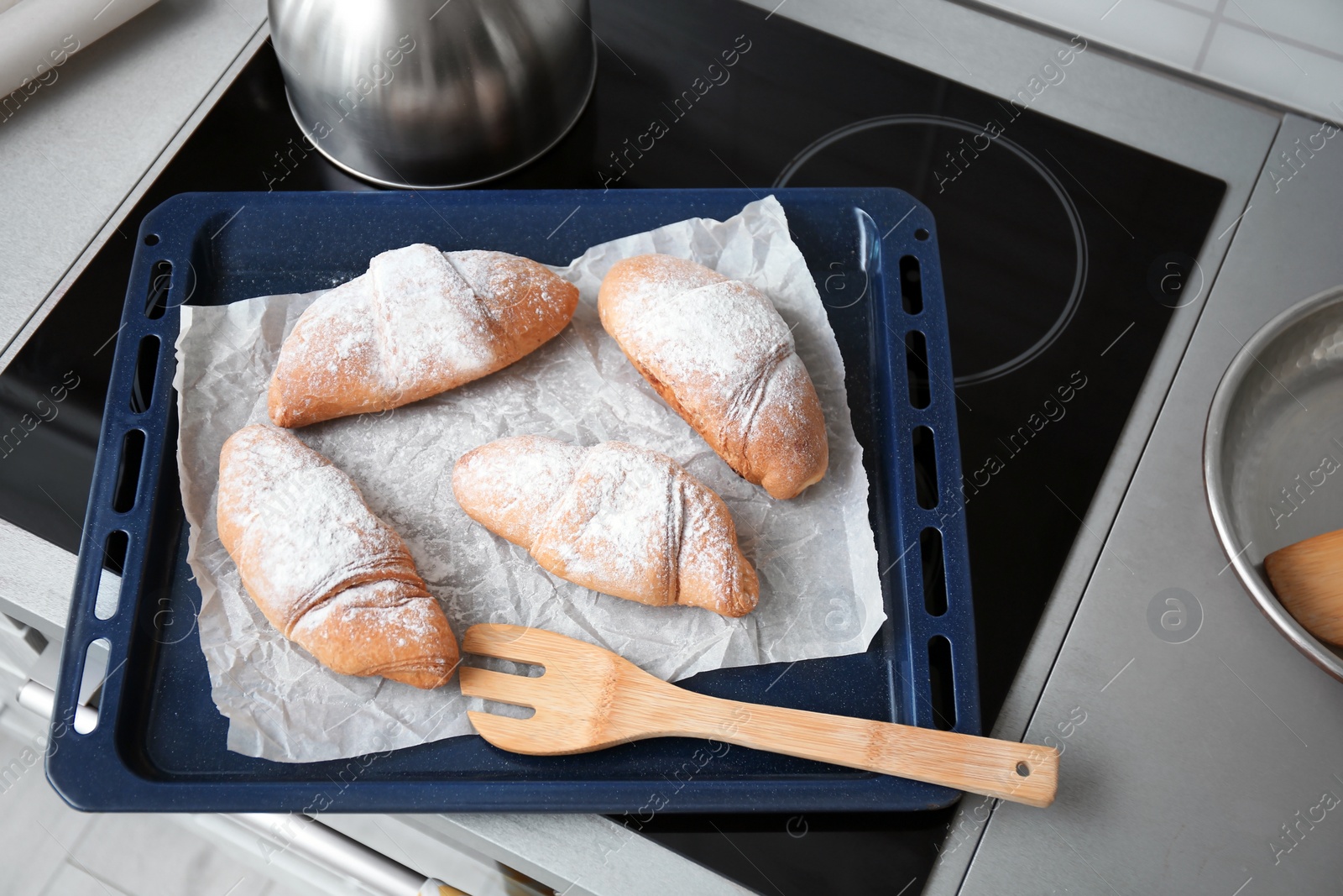 Photo of Baking tray with tasty croissants on stove