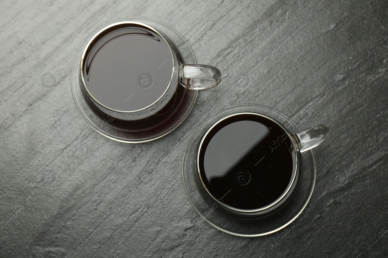 Photo of Hot coffee in cups on dark textured table, top view