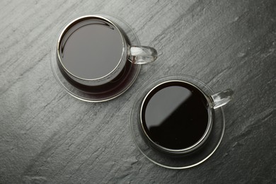 Photo of Hot coffee in cups on dark textured table, top view