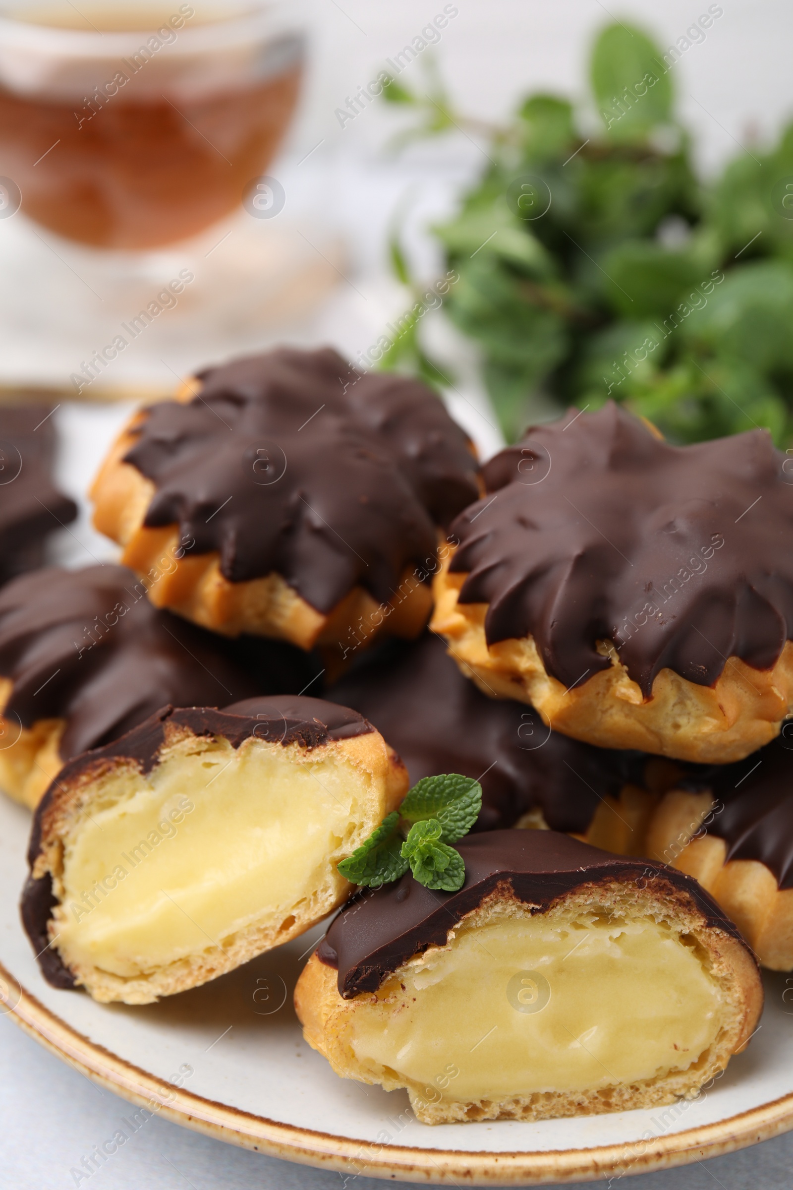 Photo of Delicious profiteroles with chocolate spread and cream on plate, closeup