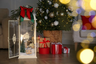 Beautiful lantern with festive composition near Christmas tree indoors