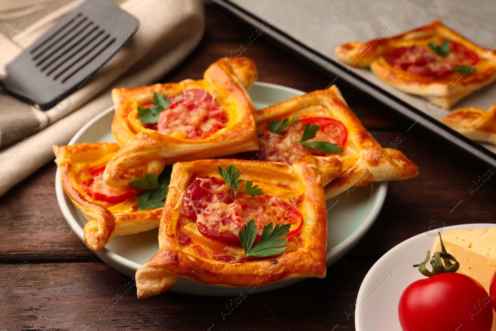 Photo of Fresh delicious puff pastry with cheese, tomatoes and parsley on wooden table, closeup