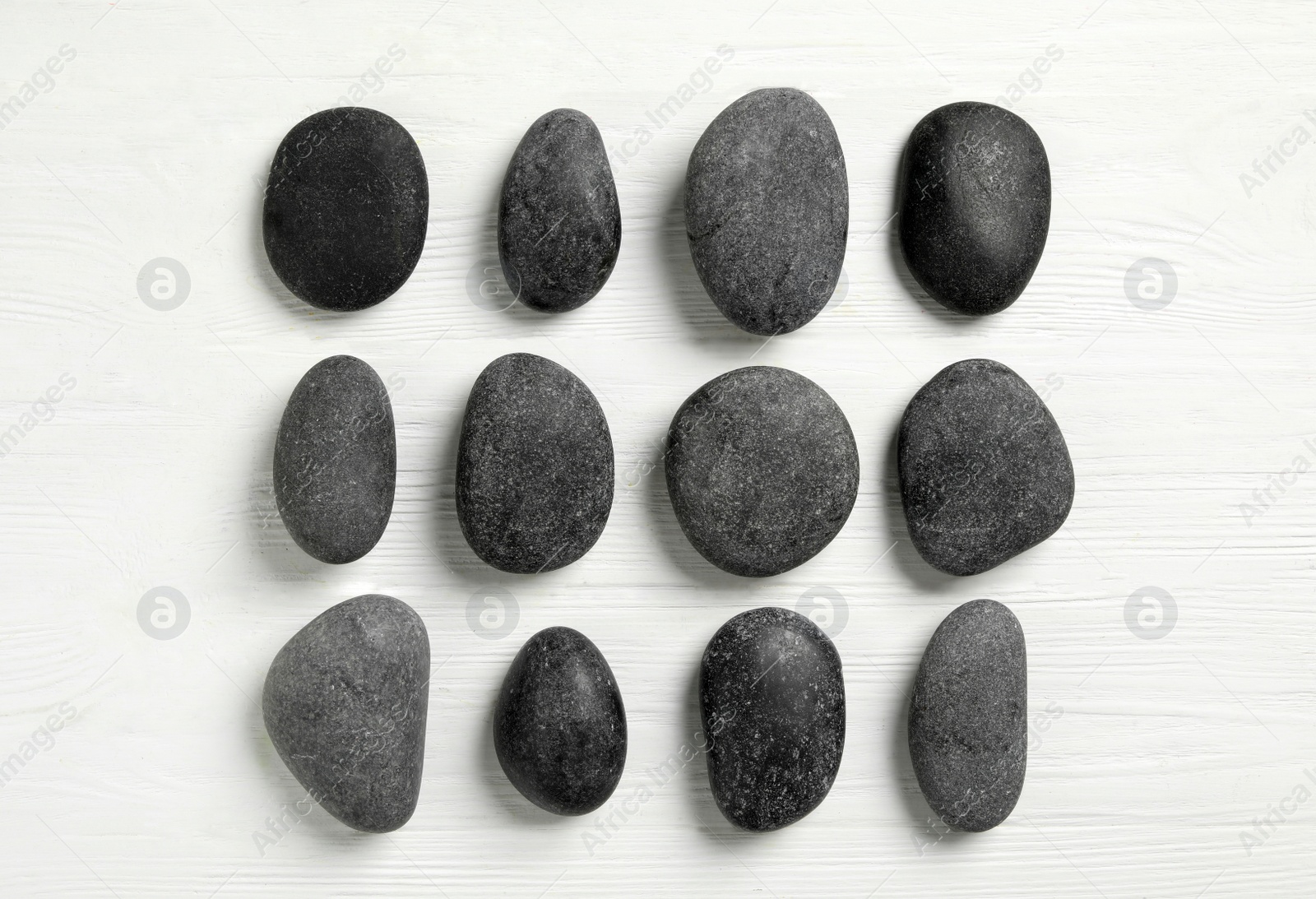 Photo of Spa stones on white wooden table, flat lay