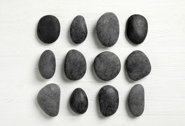 Spa stones on white wooden table, flat lay