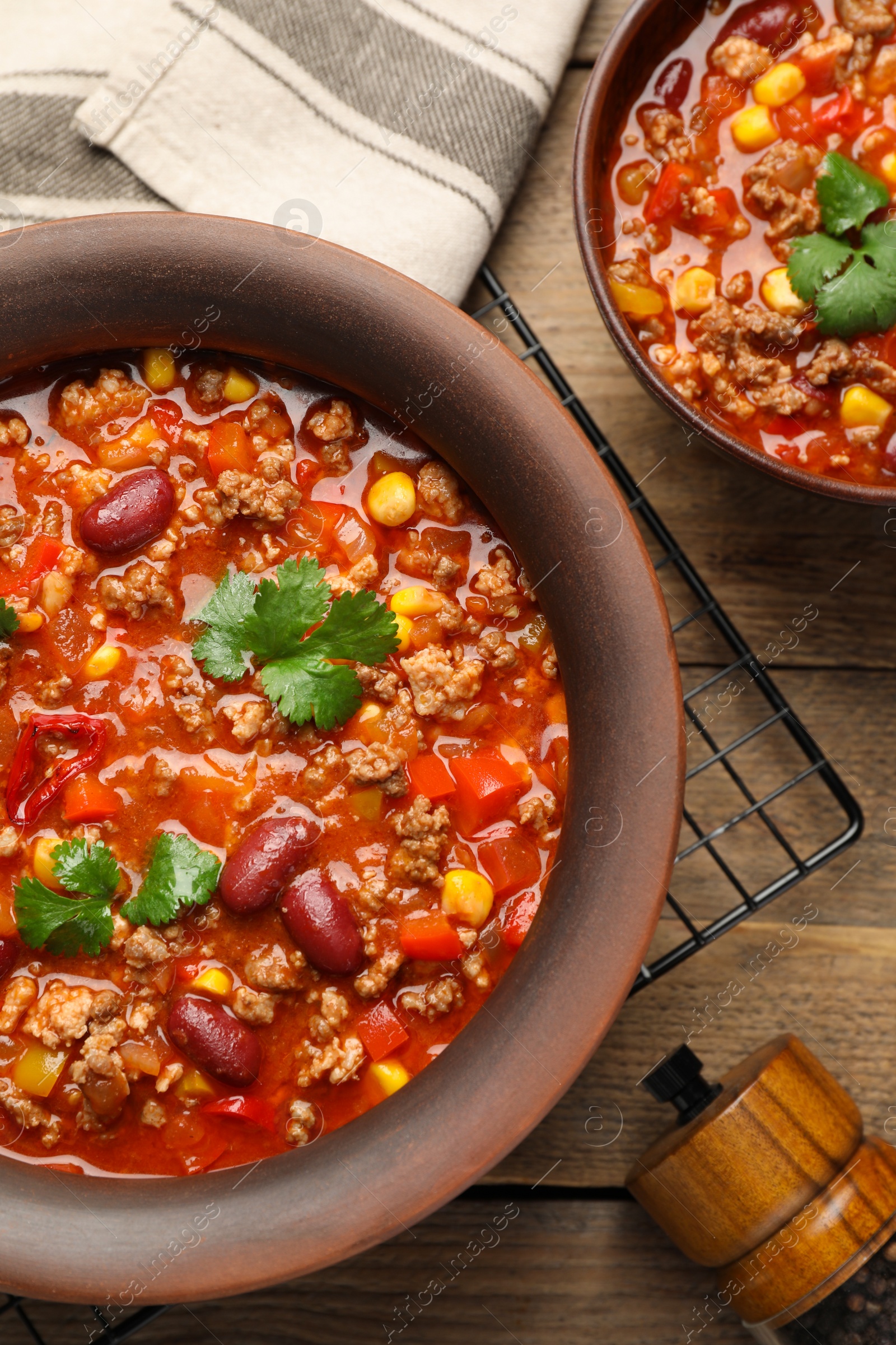 Photo of Tasty chili con carne served on wooden table, flat lay