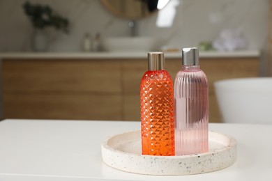 Photo of Bottles of shower gels on white table in bathroom, space for text