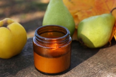 Photo of Burning candle, tasty fruits and beautiful dry leaves on wooden surface outdoors, closeup. Autumn atmosphere