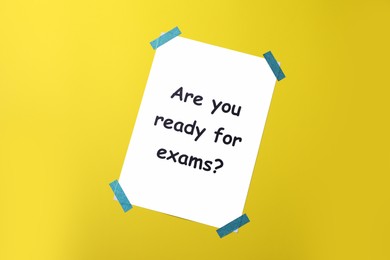 Photo of Paper with phrase Are You Ready For Exams on yellow background, top view