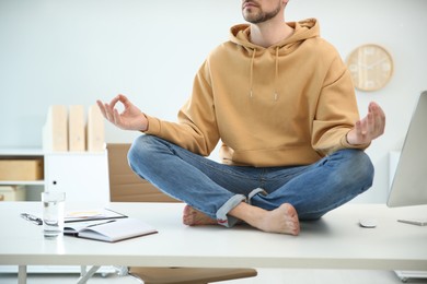 Man meditating on desk in light office, closeup