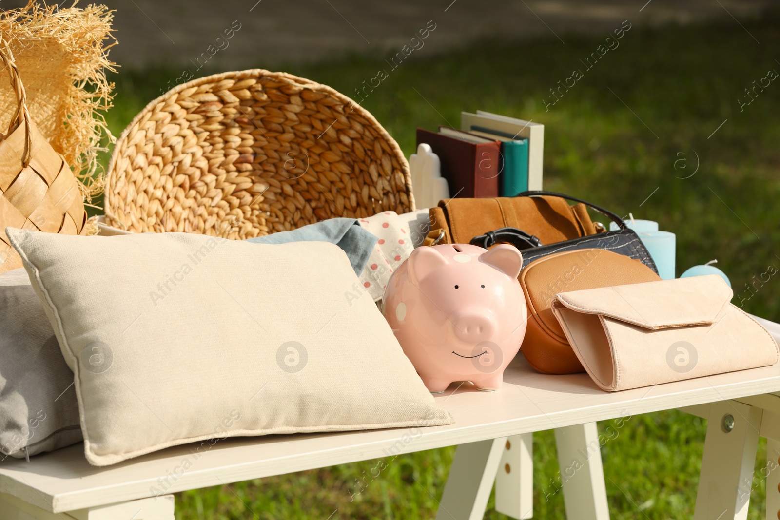 Photo of Many different items on white table outdoors. Garage sale