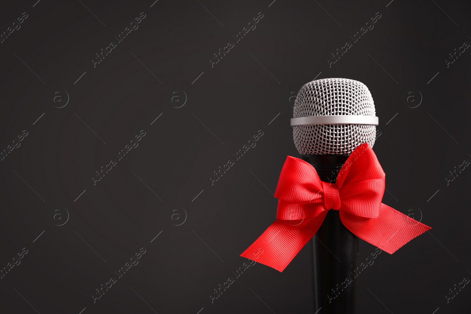 Photo of Microphone with bow on black background. Christmas music concept