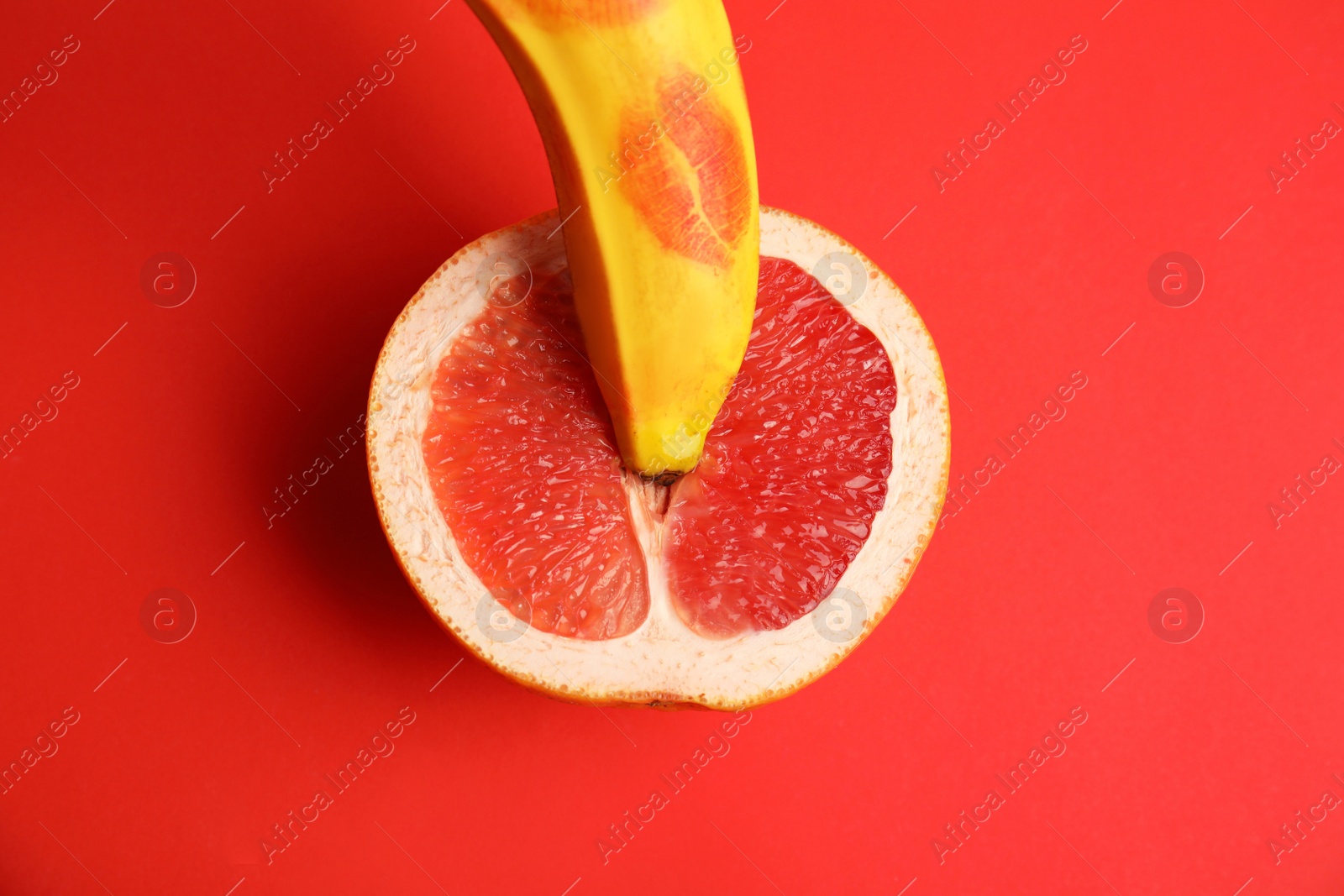 Photo of Flat lay composition with fresh banana and grapefruit on red background. Sex concept