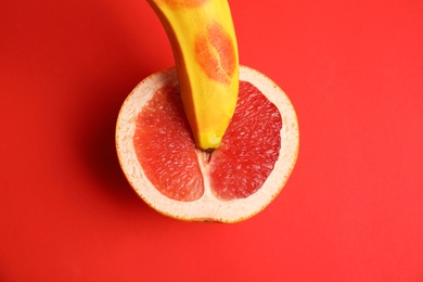 Flat lay composition with fresh banana and grapefruit on red background. Sex concept