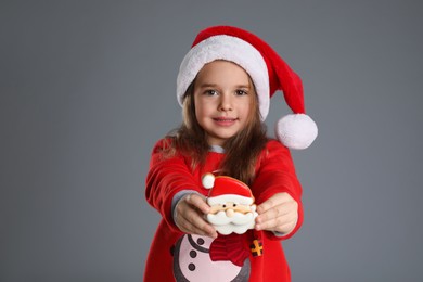 Cute little girl with Christmas gingerbread cookie on grey background