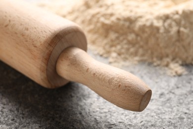 Photo of Rolling pin and scattered flour on grey textured table, closeup