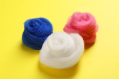 Photo of Colorful felting wool on yellow background, closeup
