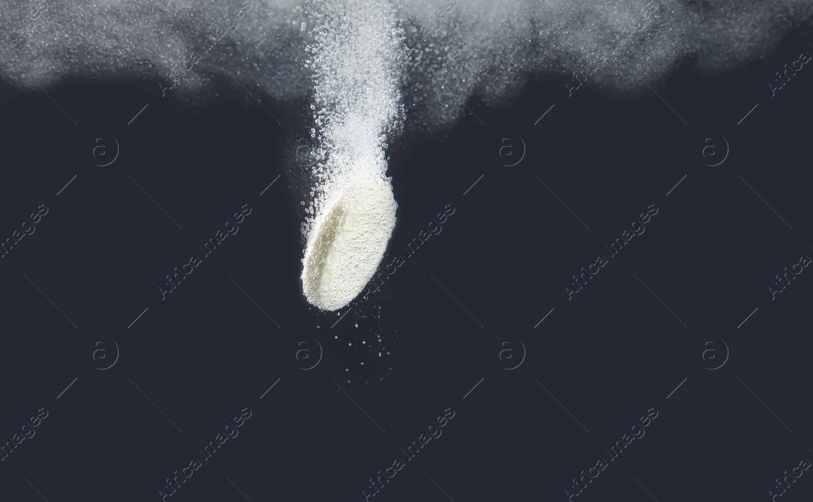 Photo of Effervescent pill dissolving in water on dark background, closeup