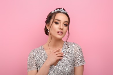 Beautiful young woman wearing luxurious tiara on pink background