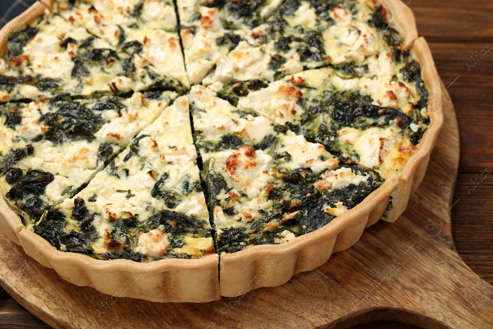 Photo of Delicious homemade spinach quiche on wooden board, closeup