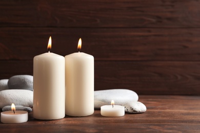 Beautiful composition with spa stones and burning candles on wooden table