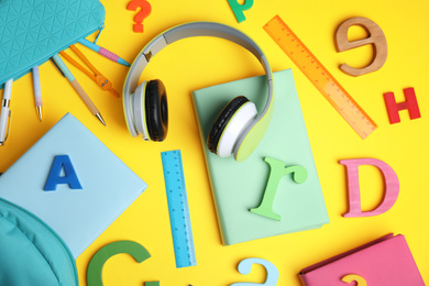 Flat lay composition with books and headphones on yellow background