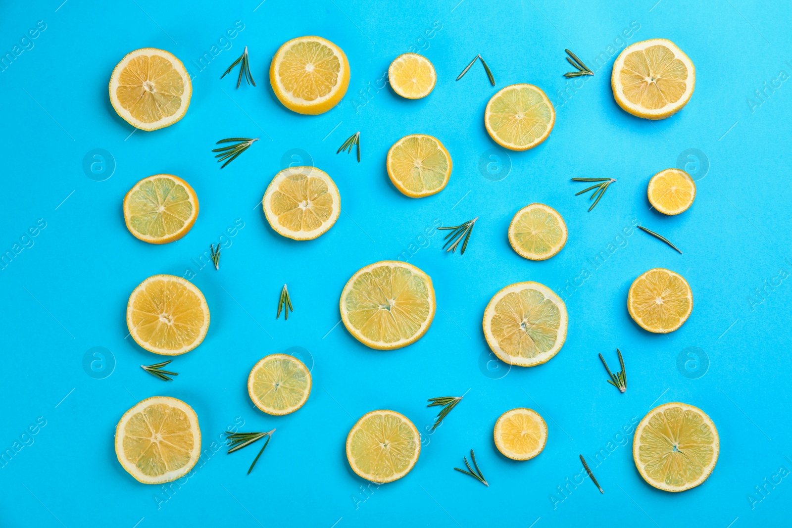 Photo of Lemonade layout with juicy lemon slices and rosemary on blue background, top view