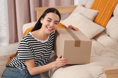 Photo of Happy young woman with parcel at home. Internet shopping