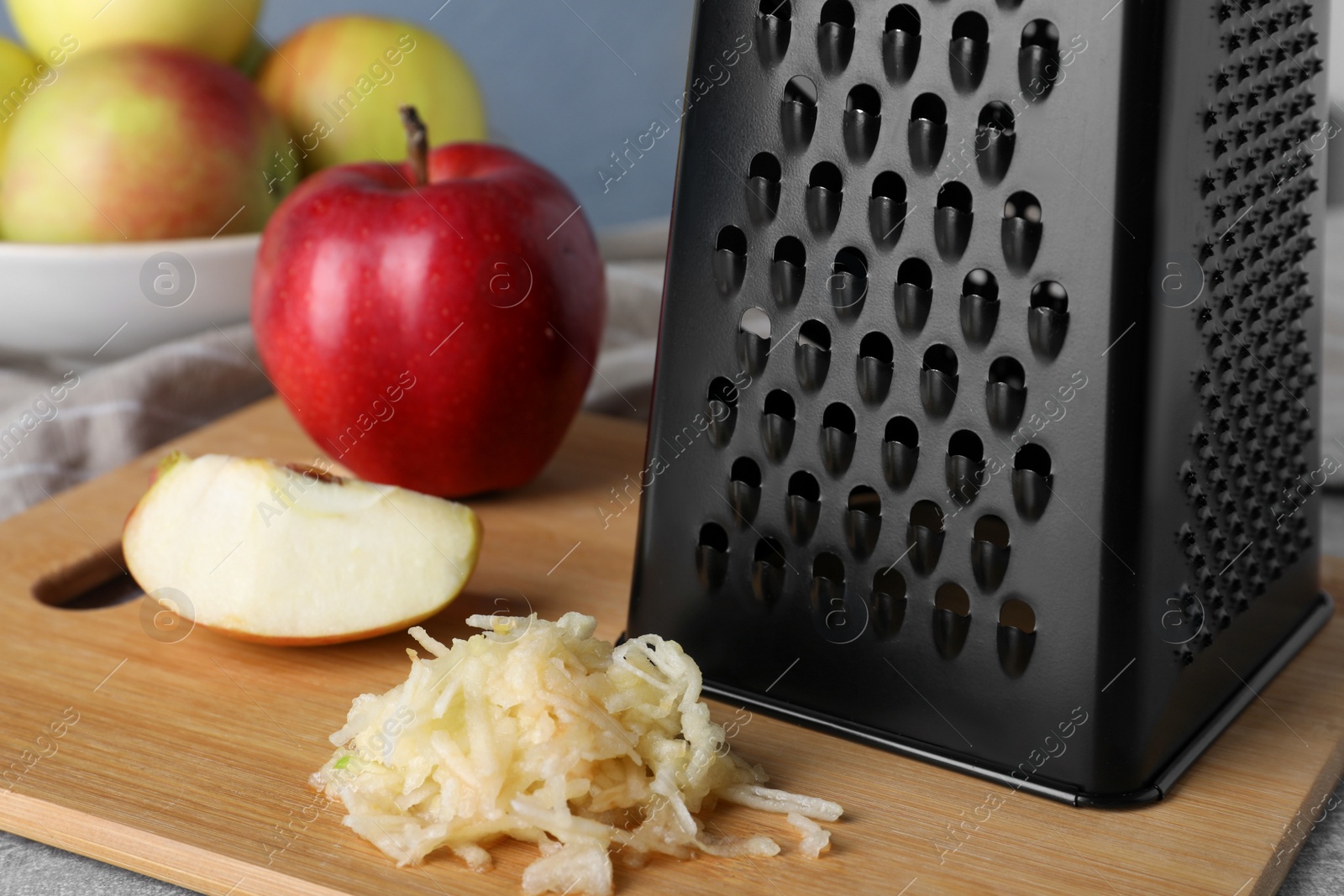 Photo of Grater and fresh ripe apple on wooden board, closeup