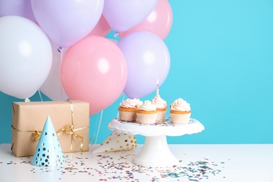 Photo of Composition with birthday cupcakes and balloons on table