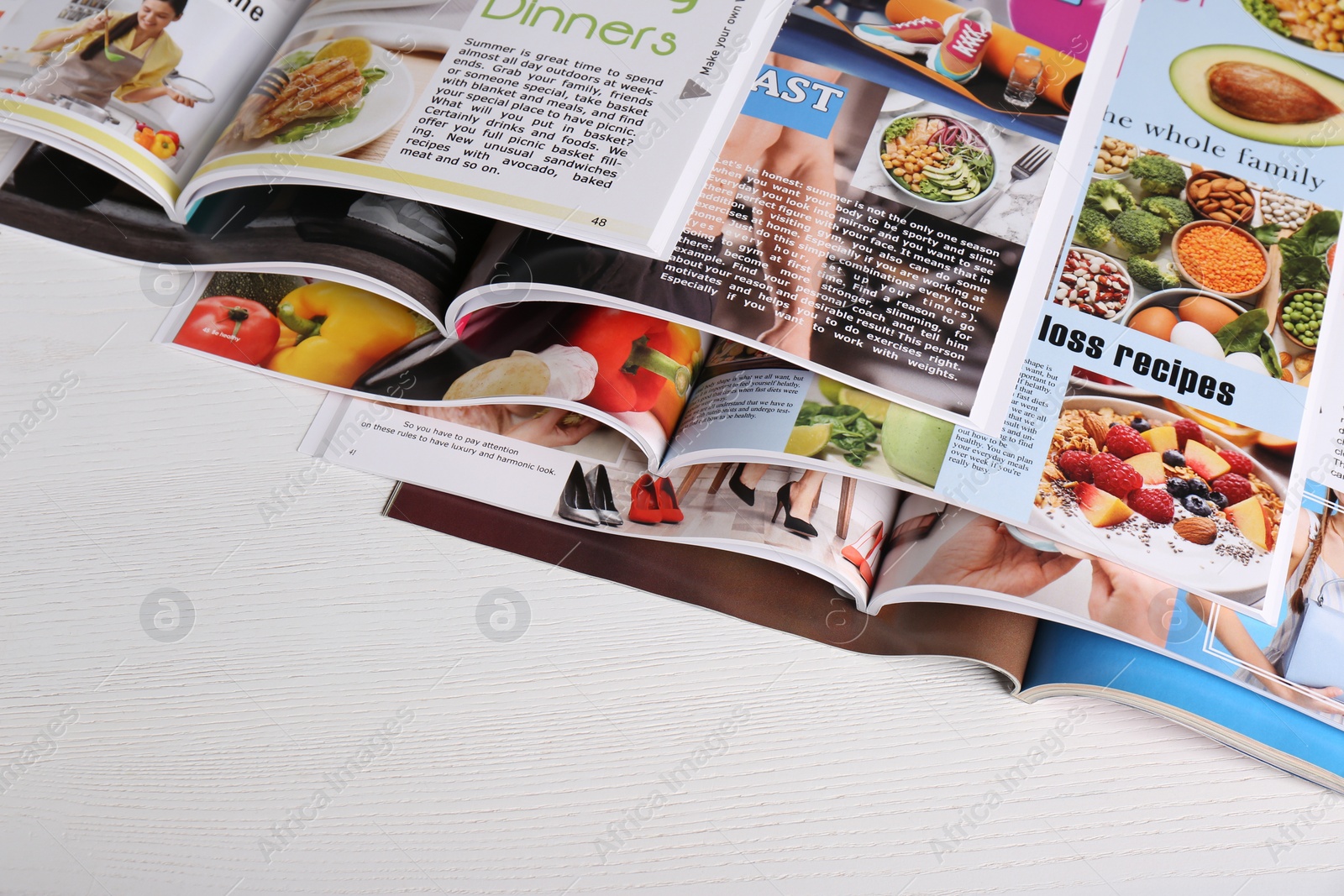 Photo of Many open magazines on white wooden table, above view