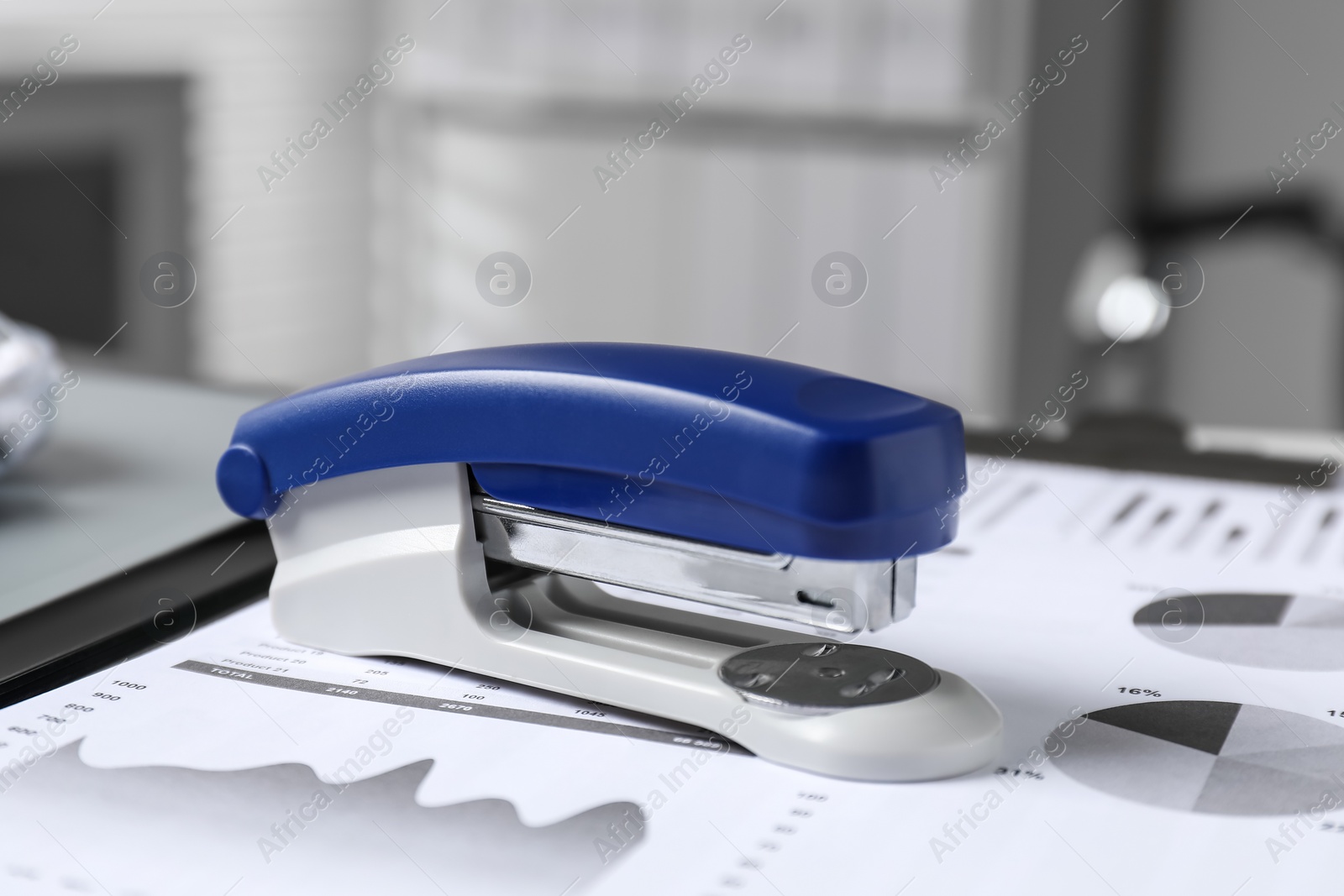 Photo of Stapler and document on table indoors, closeup