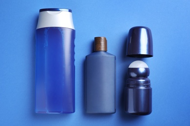 Photo of Shower gel, shampoo and roller deodorant on blue background, flat lay. Men's cosmetics