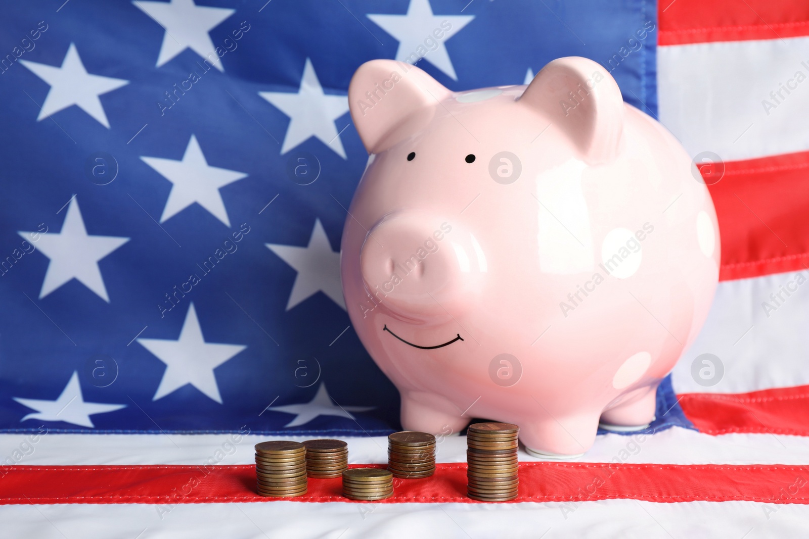 Photo of Piggy bank and stacks of coins on USA national flag