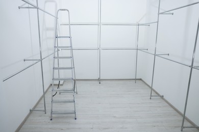 Photo of Ladder and metal pipes in empty renovated room