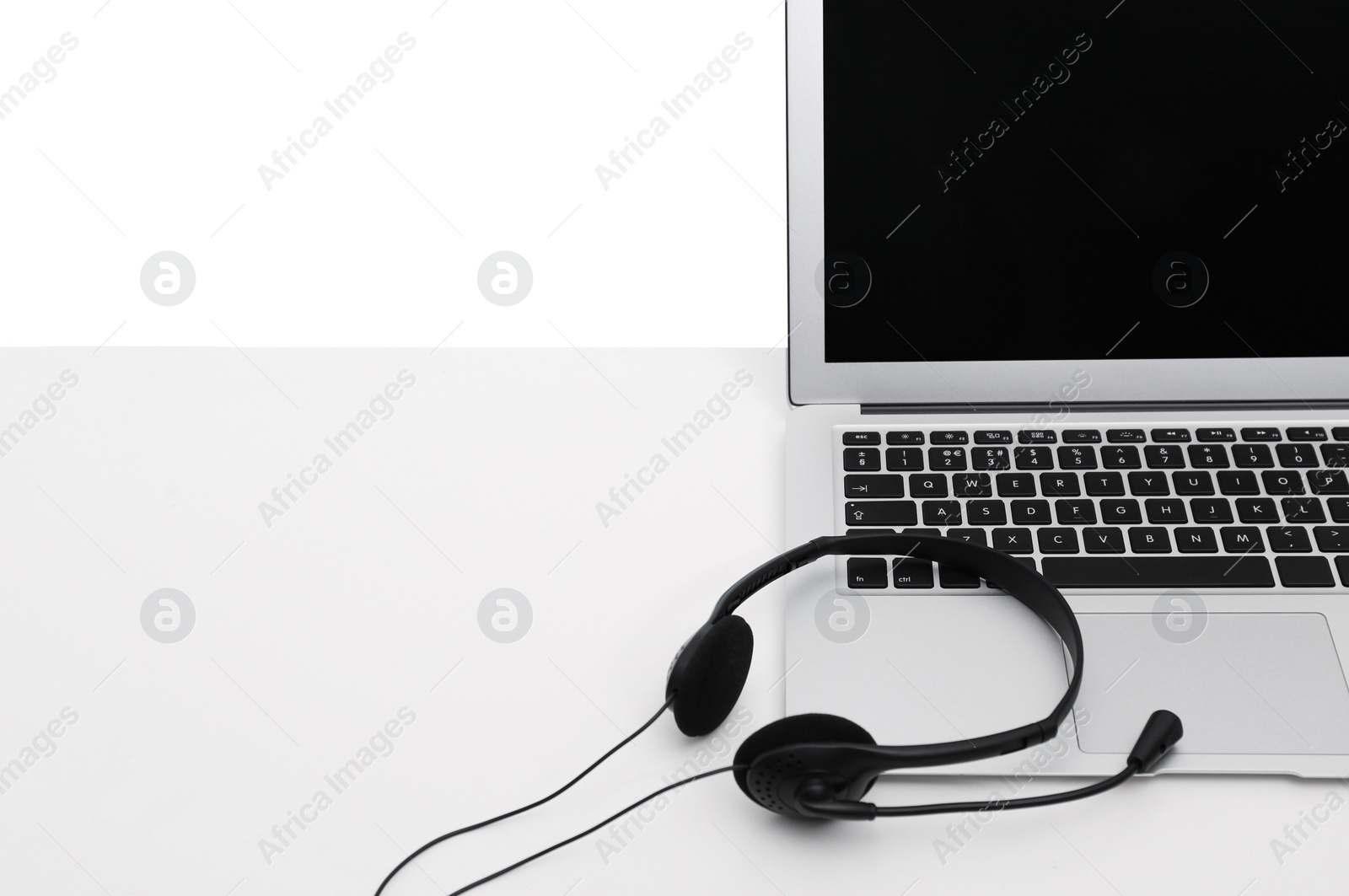 Photo of Modern laptop and headset on table, space for text. Technical support concept