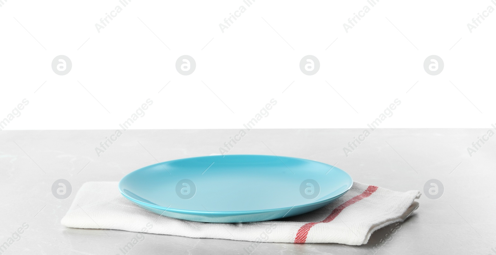 Photo of Empty blue plate and napkin on light grey table against white background