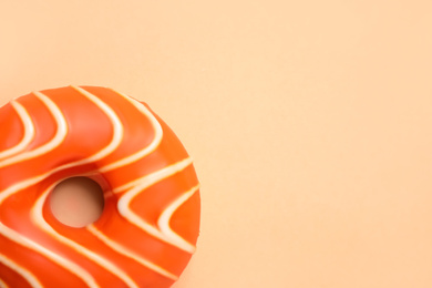 Photo of Delicious glazed donut on orange background, top view. Space for text