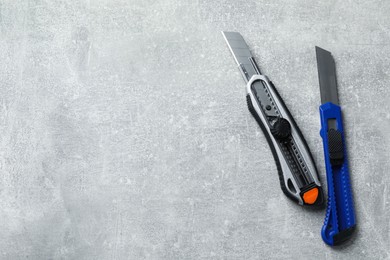 Photo of Different utility knives on light grey table, flat lay. Space for text
