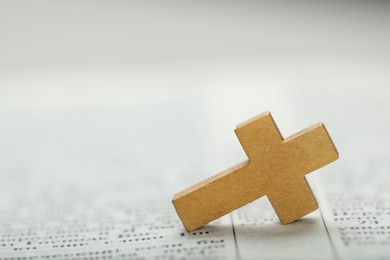 Photo of Christian cross on Bible, closeup. Space for text