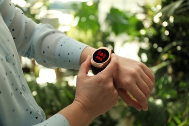 Woman using SOS function on smartwatch outdoors, closeup