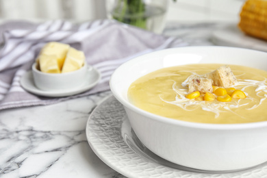 Photo of Delicious corn cream soup served on white marble table, closeup. Space for text